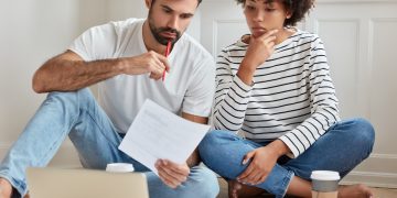 Casal conferindo dívidas para realizar o pagamento por meio do serasa limpa nome e desenrola brasil.