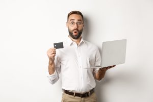 Homem segurando um computador e um cartão de crédito MEI.