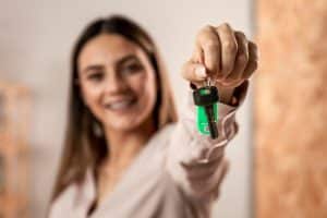 Mulher feliz com chave em mãos ao entender como comprar apartamento sozinho.