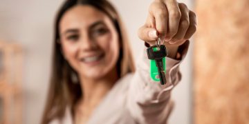 Mulher feliz com chave em mãos ao entender como comprar apartamento sozinho.