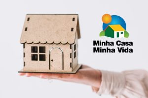 pessoa segurando casa em miniatura ilustrativa para minha casa minha vida cidades.