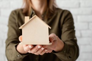 Mulher segurando casa em miniatura após conferir novidades minha casa minha vida.