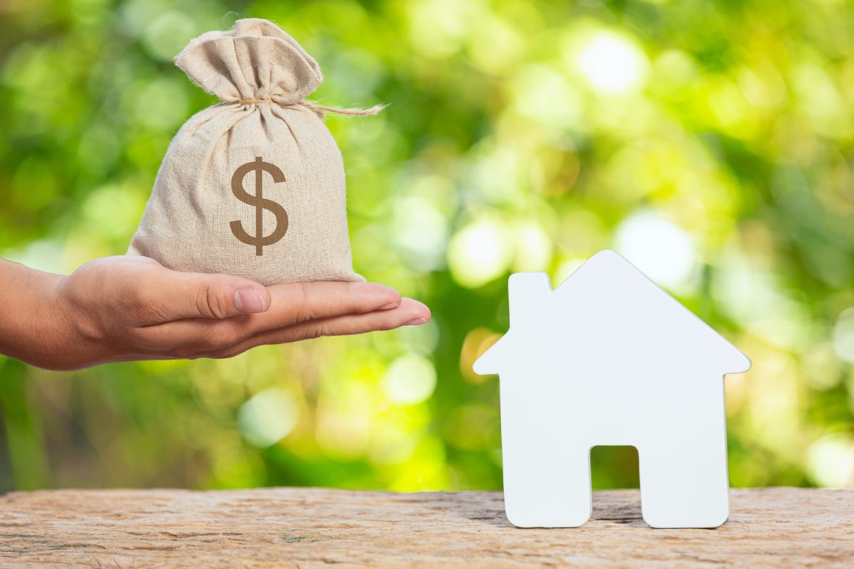 Dinero y casa en miniatura que representan préstamos hipotecarios en Colombia.
