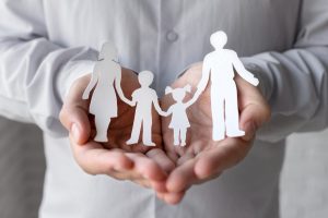 Imagem ilustrativa com família feita em papel para ilustrar conteúdo sobre a Regra de proteção no Bolsa Família.
