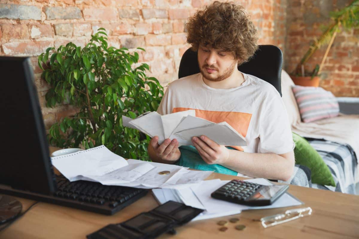 Rapaz tentando se organizar financeiramente e quitar dívidas.