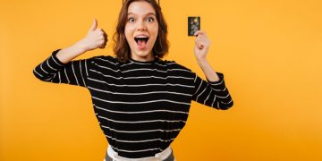 Mujer feliz con su tarjeta Scotiabank Visa Signature.