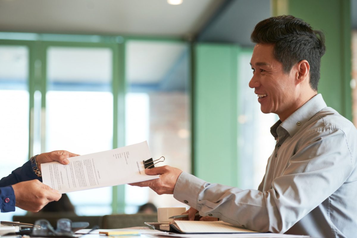 Hombre entregando un certificado de propiedad bancaria a un cliente.