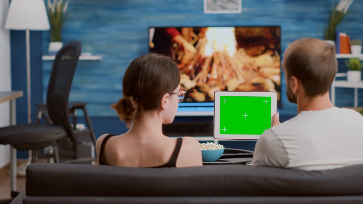 Família utilizando dispositivo digital em casa enquanto acompanha conteúdos de mídia